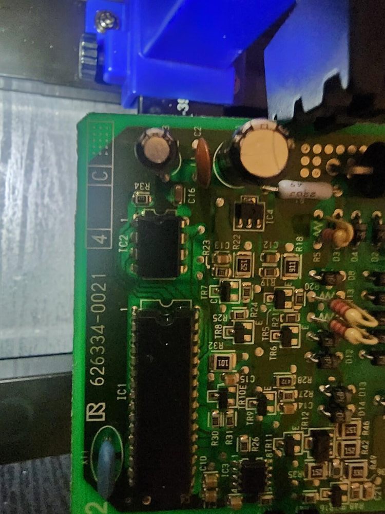 Close-up of a vehicle module circuit board clamped for direct EEPROM chip reading