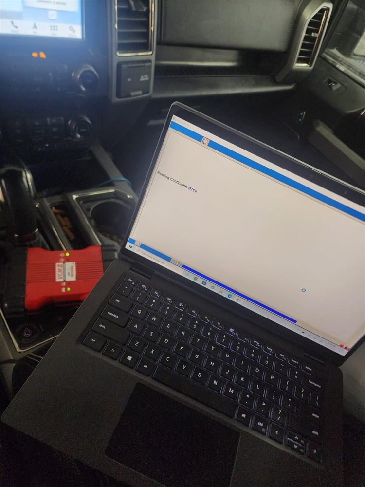Laptop running Ford factory diagnostic software connected to a truck by a VCM II interface