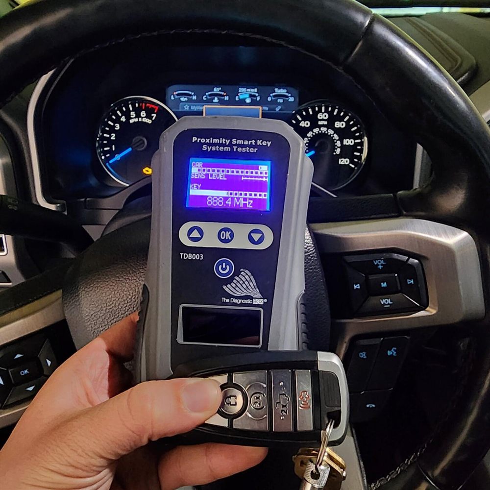 Proximity smart key system tester reading a key fob's frequency inside a vehicle cab